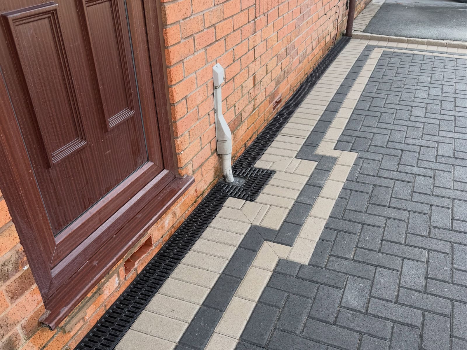 Charcoal herringbone side path with decorative buff border and Aco drain