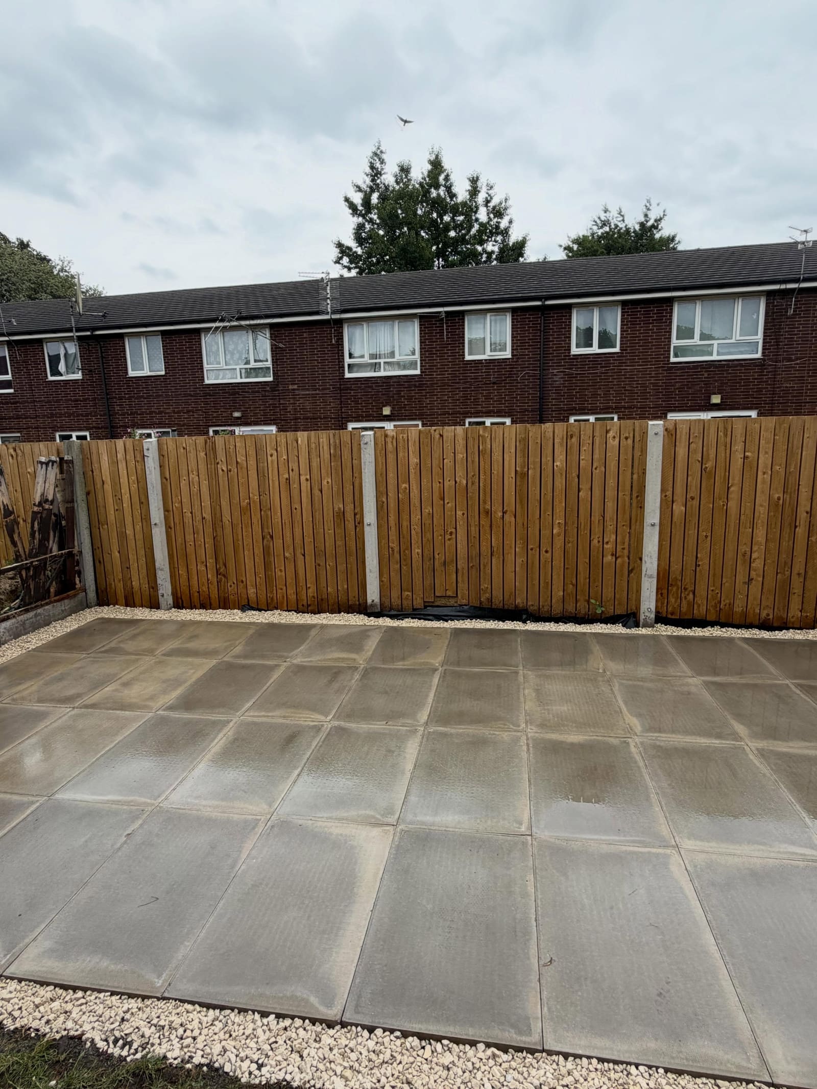 Concrete-post lap fence overlooking new grey slab patio with shingle edge Cheshire