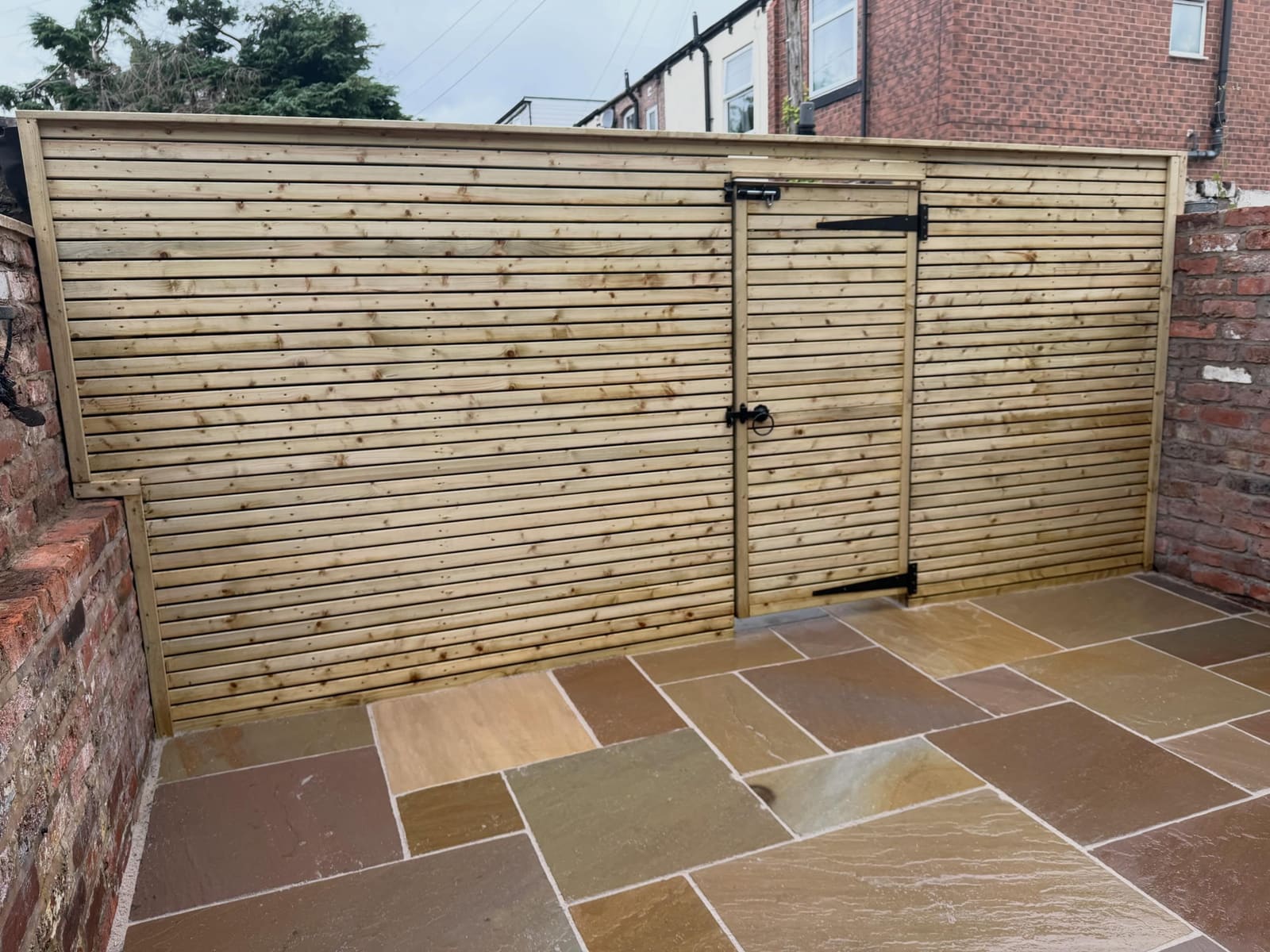 Contemporary horizontal slatted timber gate set in sandstone patio courtyard