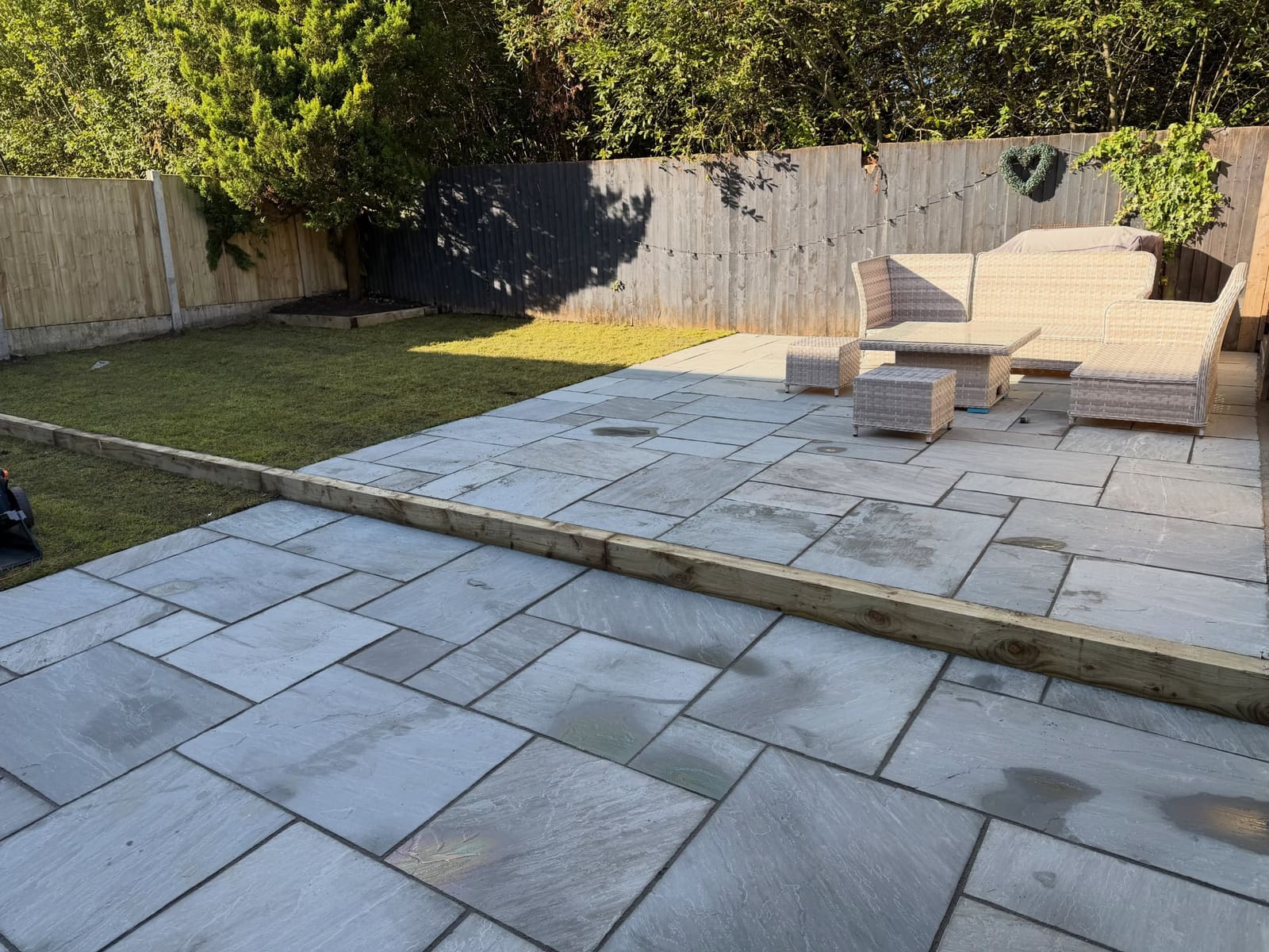 Light grey sandstone flags with railway sleeper accent and garden furniture