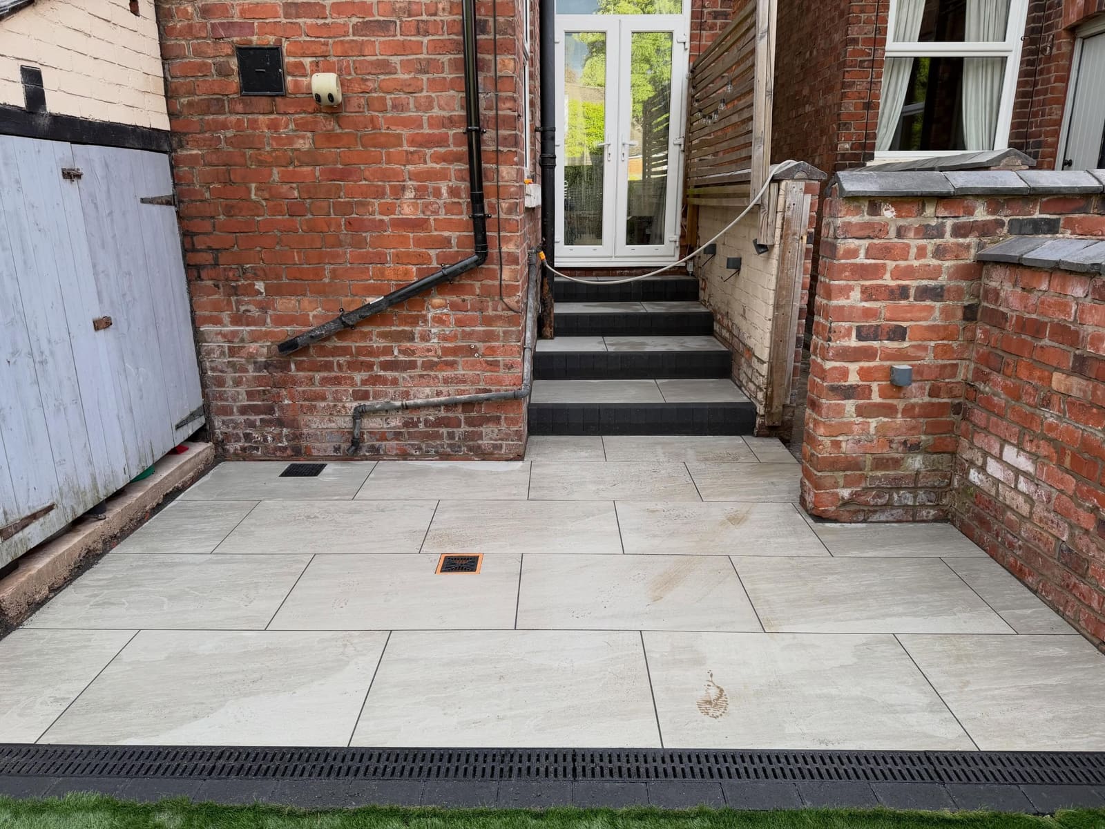 Porcelain patio steps with charcoal block risers leading to French doors Manchester
