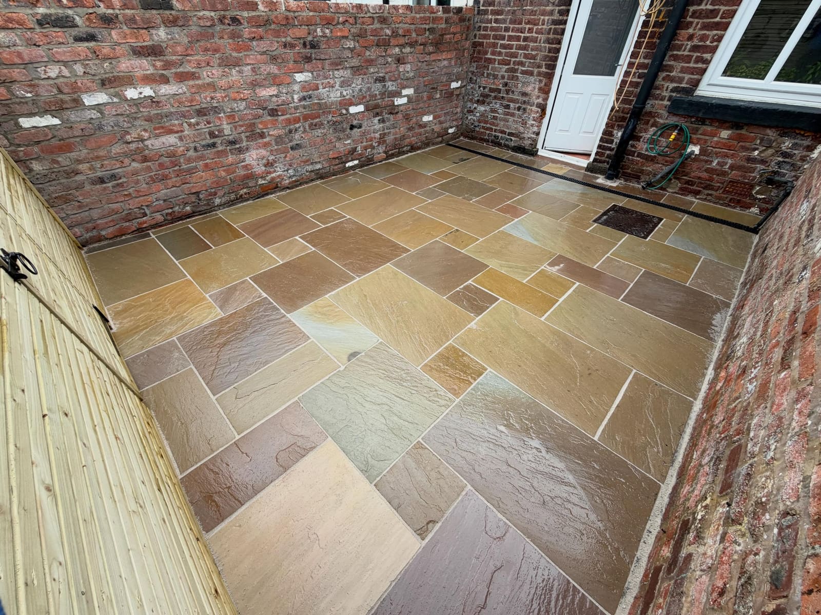 Multi-tonal sandstone courtyard with brick walls and integrated channel drain