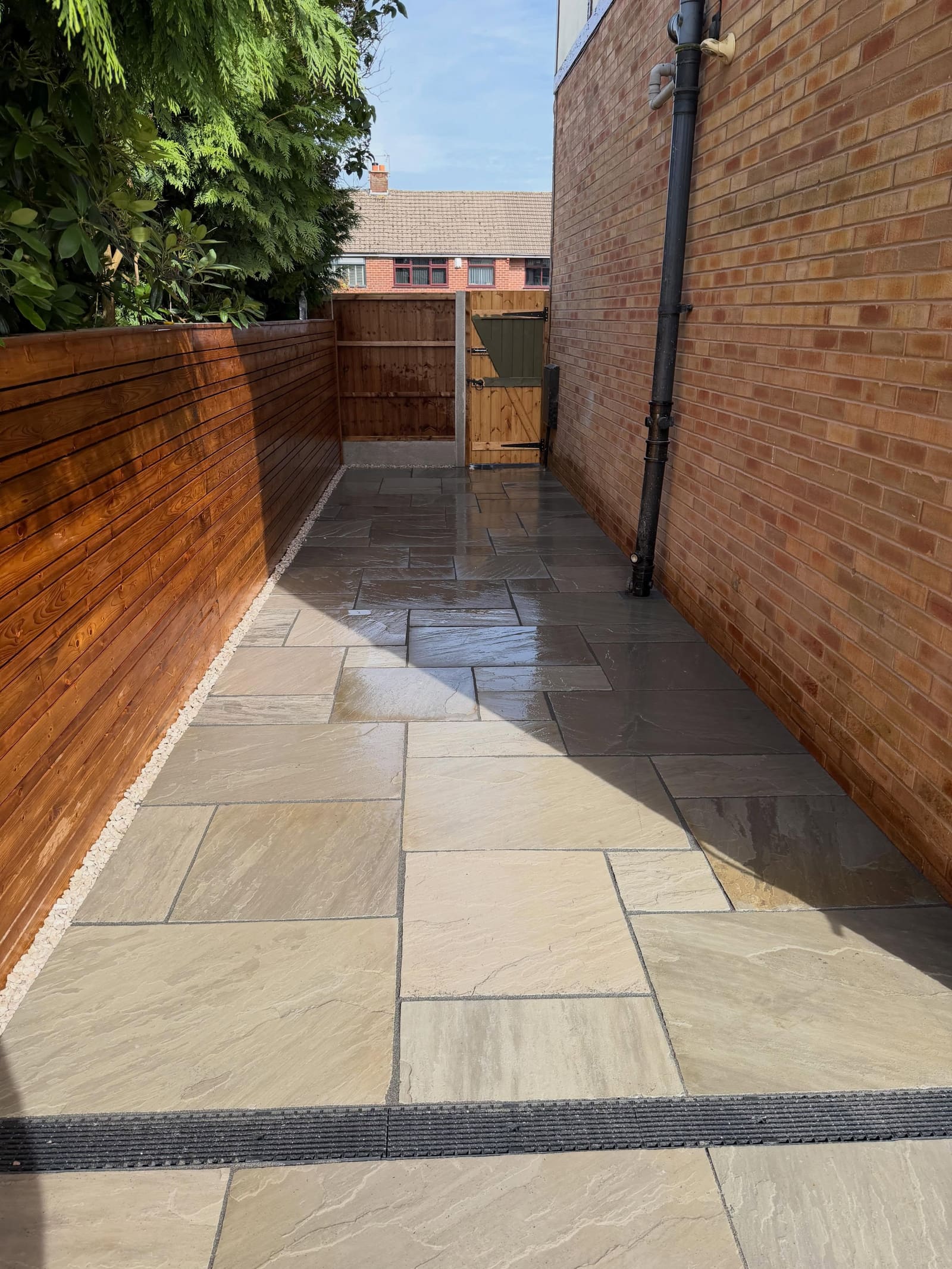Buff Indian sandstone side passage with horizontal slat fence and gravel Manchester