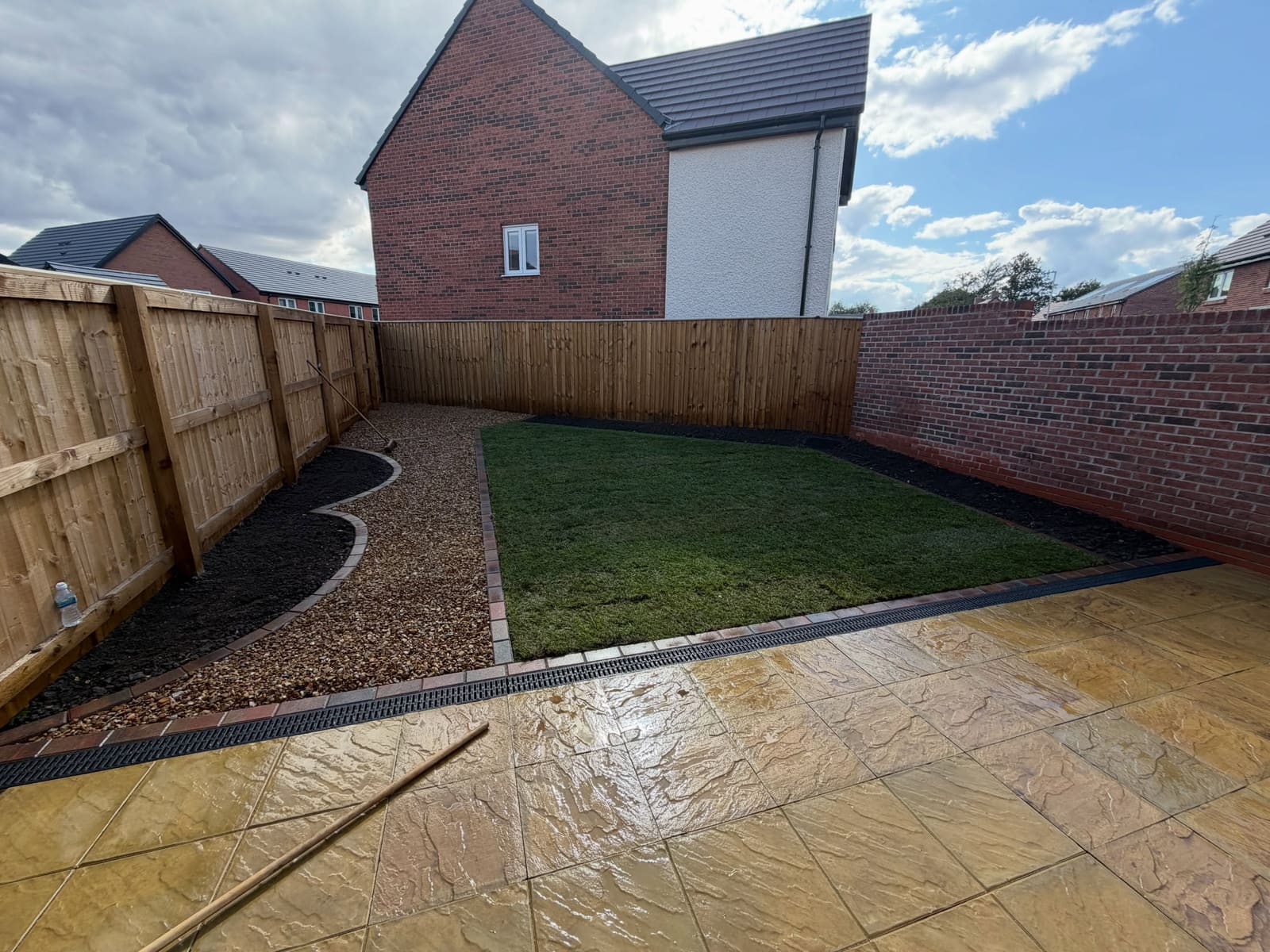 Buff riven sandstone patio with fresh turf and golden gravel pathway