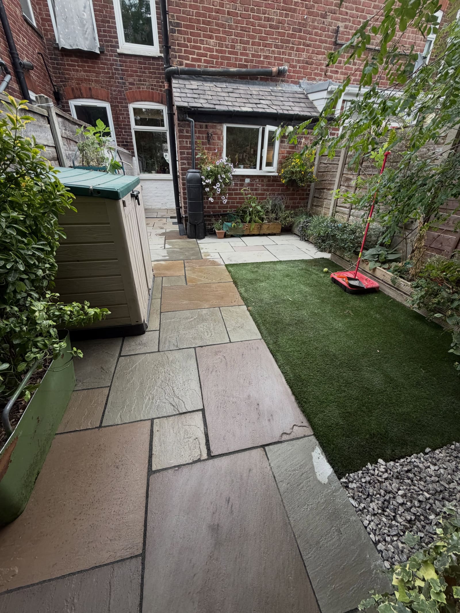 Multi-colour sandstone patio with artificial turf patch and slate chippings