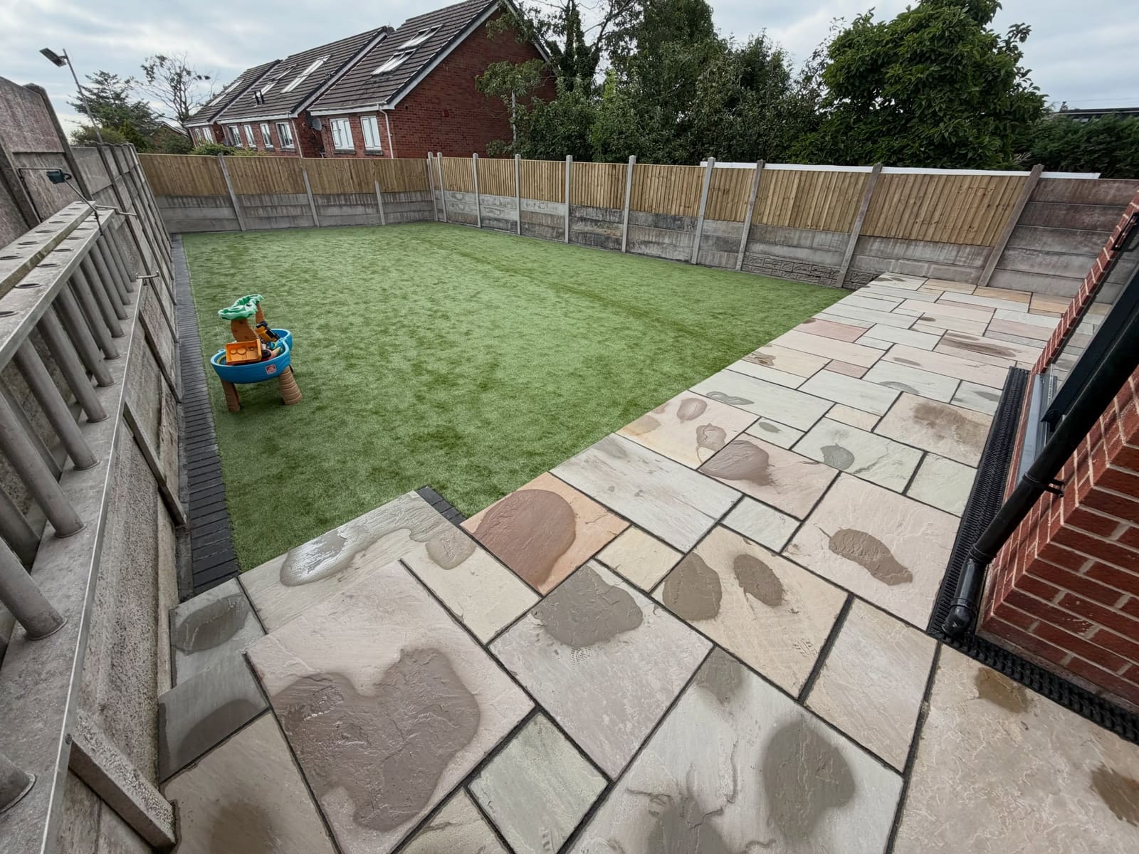 Sandstone patio with artificial grass lawn and new featheredge fence Cheshire