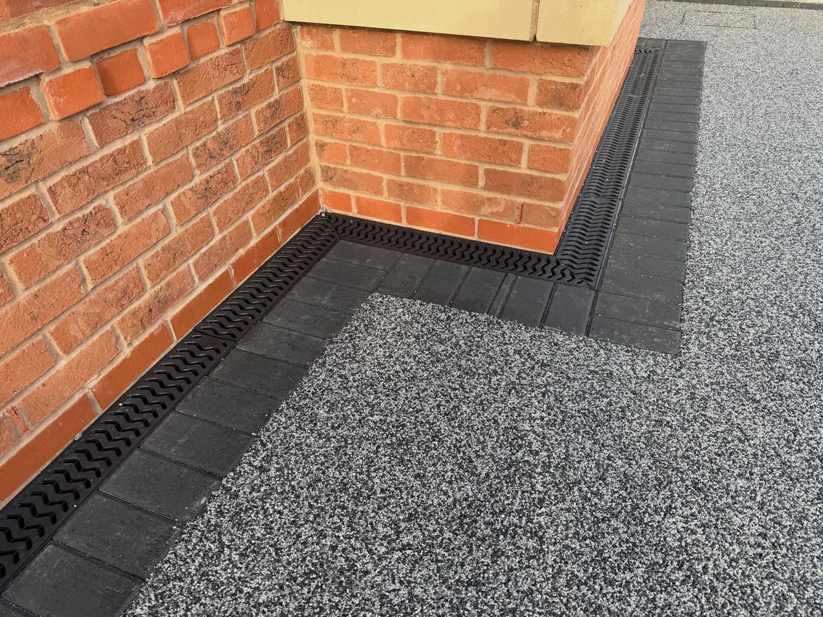 Salt-and-pepper grey resin bound finish with soldier course and slot drain