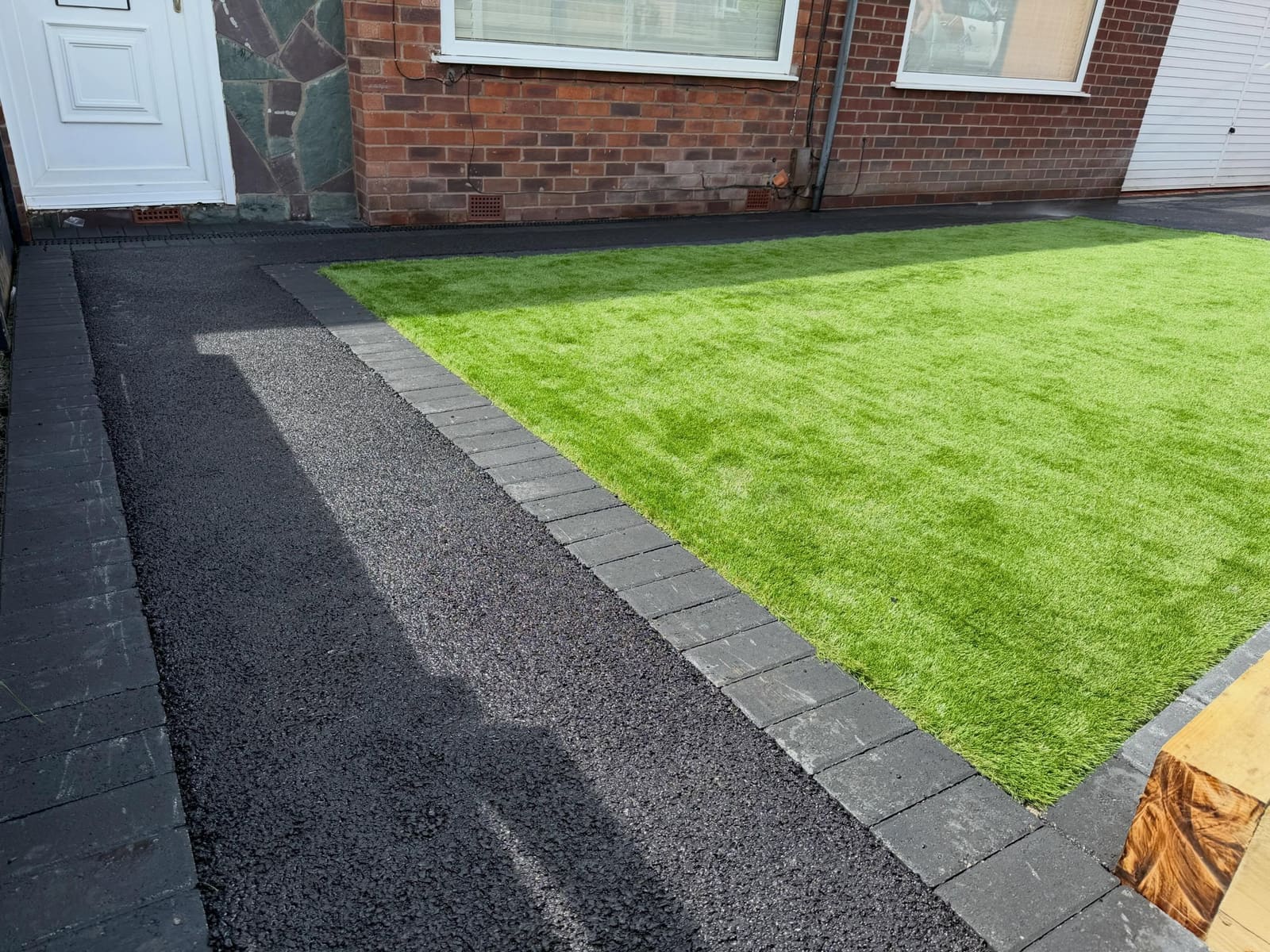 Fresh tarmac walkway edged with blocks beside slate-clad porch
