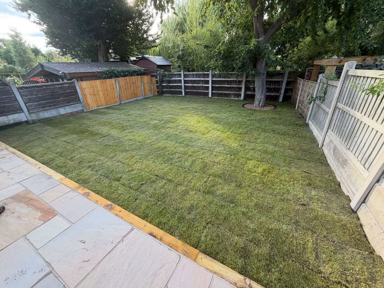 Freshly rolled real turf lawn with sandstone patio and sleeper border