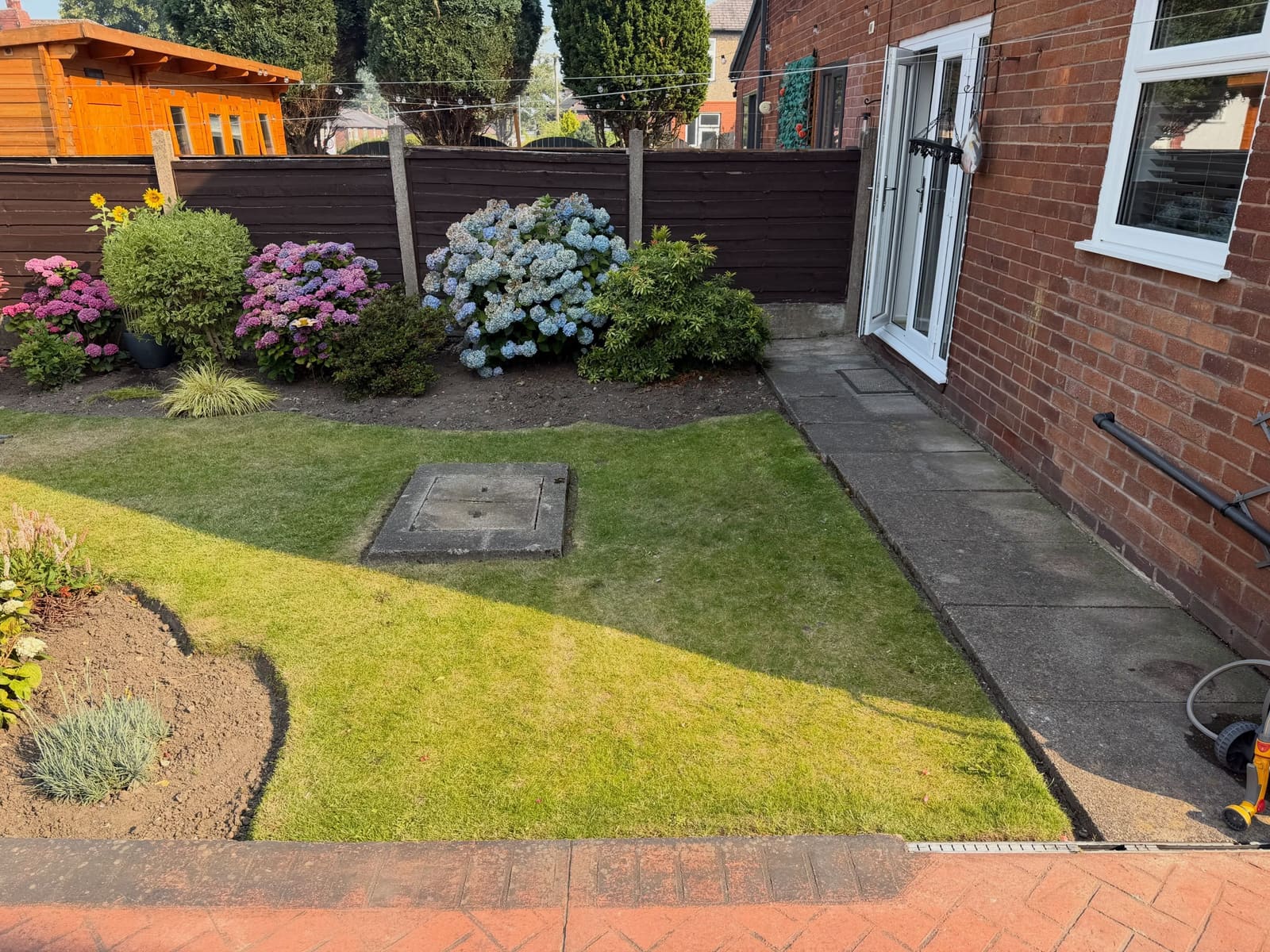 Lush real turf beside block paving drain channel and grey slab path Manchester